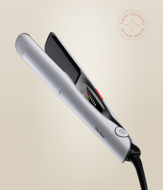 Pearl White Omnia Styler Plus held open at an angle, showing black plates, temperature controls and cord.